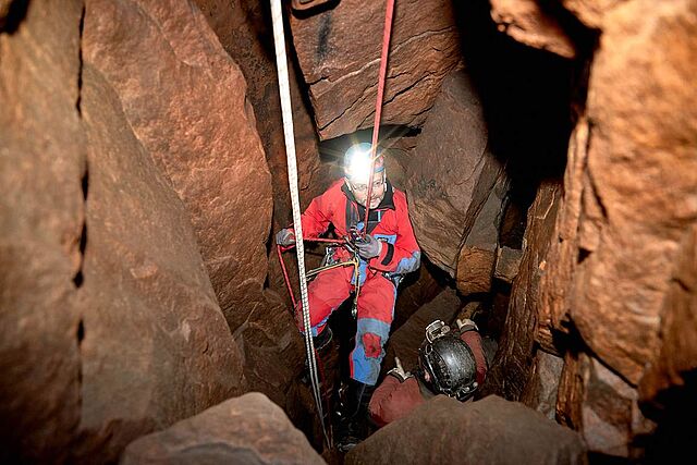 Ein Bergretter seilt sich in eine Höhle ab.